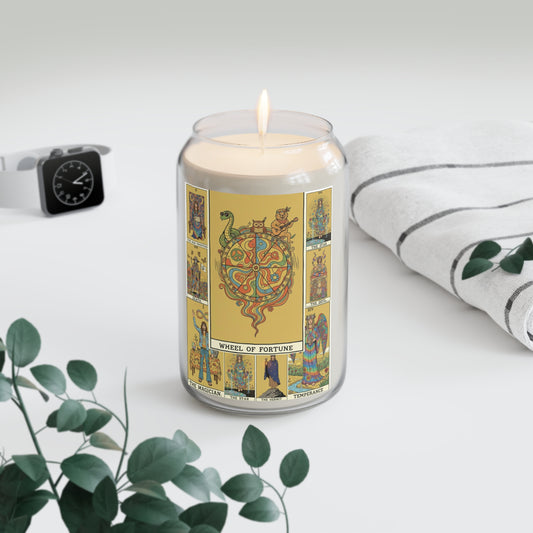 Candle in a jar with Tarot design on a white surface with a plant and watch in the background